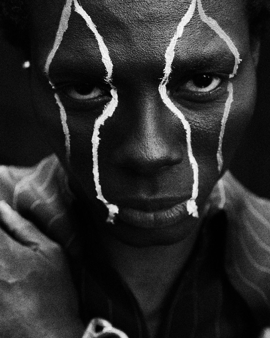 Black and white close-up portrait with painted white lines on the face