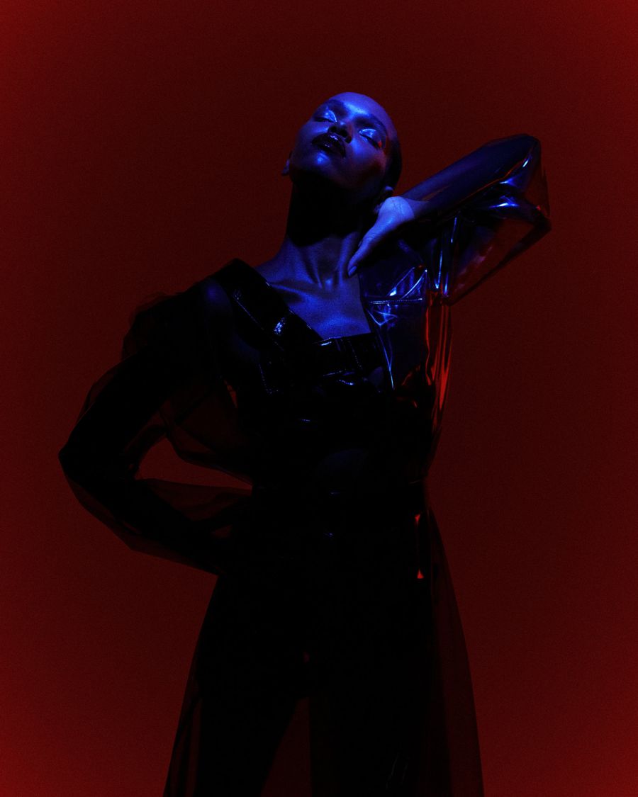 Editorial portrait in red and blue light with glossy blue eye makeup